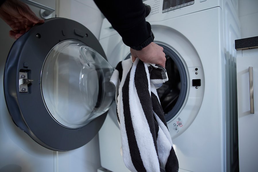 En person som lägger in tvätt i en tvättmaskin