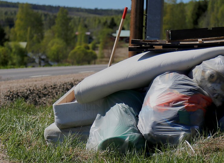 Grovsopor som ligger på gräset längs en grusväg.
